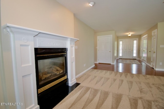 interior space with baseboards, a glass covered fireplace, and wood finished floors
