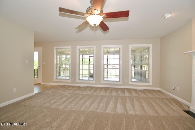 unfurnished living room featuring carpet floors, baseboards, and plenty of natural light