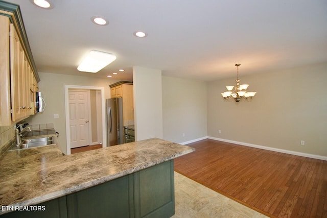 kitchen with appliances with stainless steel finishes, a sink, a peninsula, a chandelier, and recessed lighting