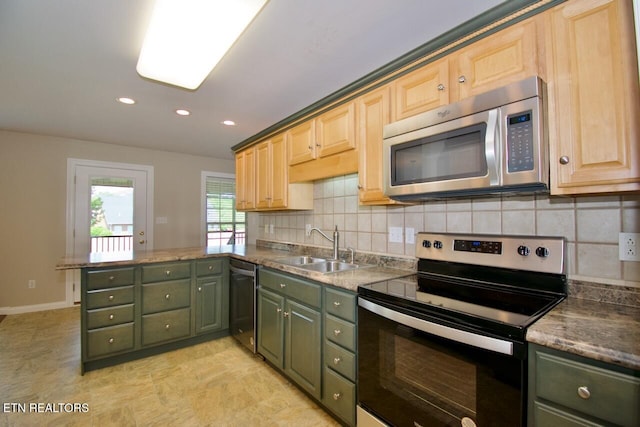 kitchen featuring tasteful backsplash, a sink, green cabinets, a peninsula, and stainless steel appliances