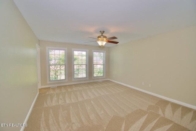 unfurnished room featuring baseboards, a ceiling fan, visible vents, and light colored carpet