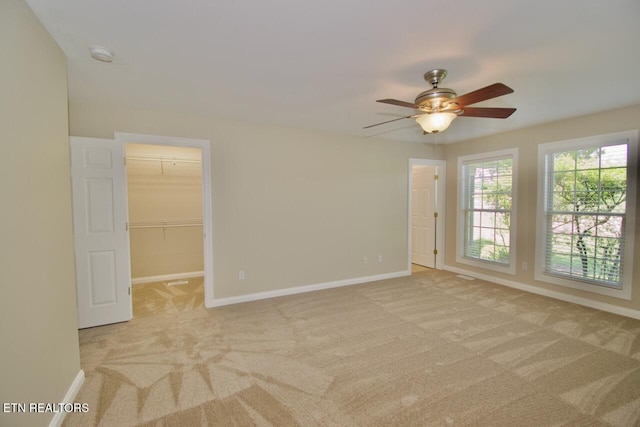 unfurnished room with baseboards, a ceiling fan, and light carpet
