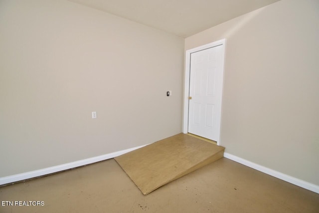 spare room featuring baseboards and finished concrete floors