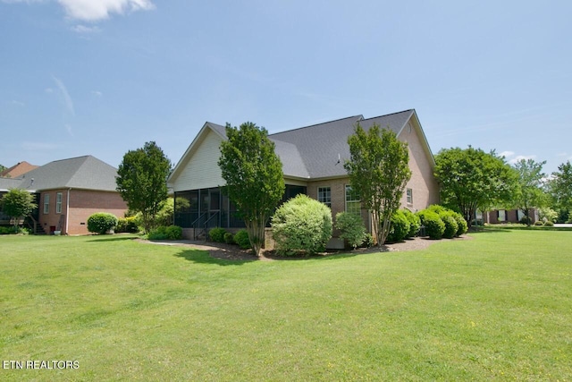view of side of home featuring a sunroom and a lawn