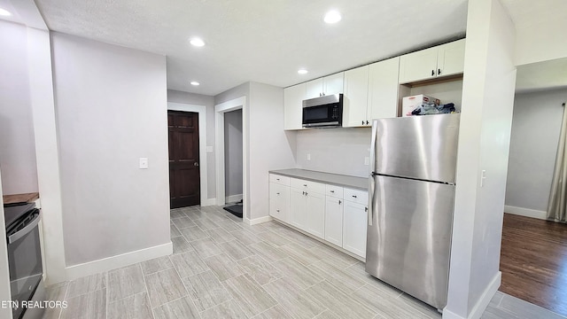 kitchen featuring appliances with stainless steel finishes, light wood-type flooring, baseboards, white cabinets, and recessed lighting