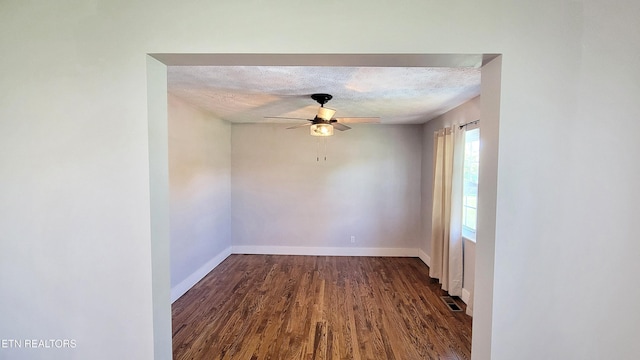 empty room featuring a ceiling fan, a textured ceiling, dark wood finished floors, and baseboards