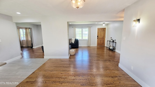 hall featuring baseboards, recessed lighting, and wood finished floors