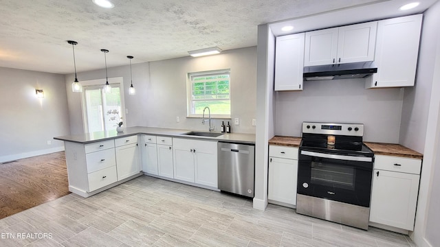 kitchen with a sink, stainless steel appliances, white cabinetry, a peninsula, and under cabinet range hood