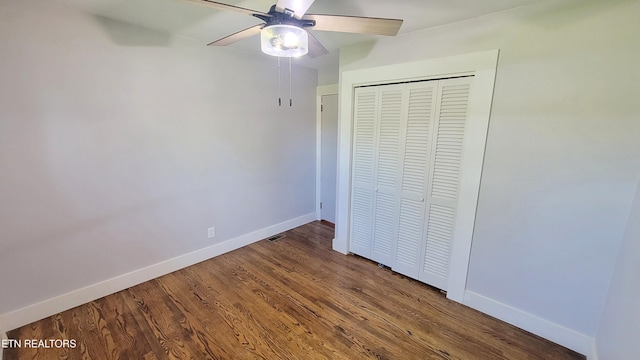 unfurnished bedroom with baseboards, a ceiling fan, wood finished floors, and a closet