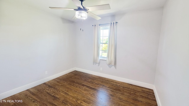 spare room with baseboards, a ceiling fan, and dark wood-type flooring