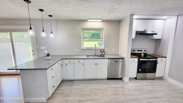 kitchen featuring a peninsula, white cabinetry, under cabinet range hood, a sink, and appliances with stainless steel finishes