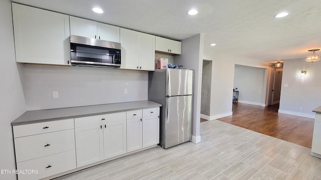kitchen with stainless steel appliances, baseboards, recessed lighting, and white cabinetry