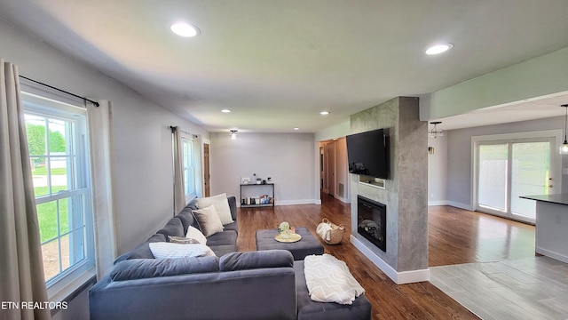 living room with recessed lighting, baseboards, a large fireplace, and wood finished floors