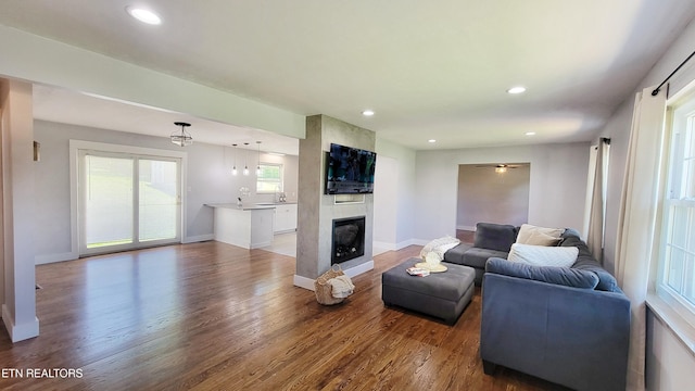 living room featuring a ceiling fan, a fireplace, wood finished floors, baseboards, and recessed lighting