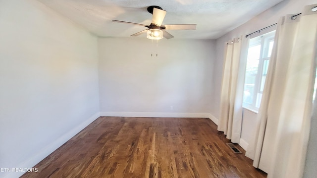 spare room featuring baseboards, ceiling fan, dark wood-style floors, and visible vents