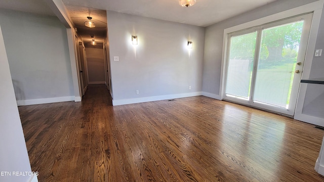 unfurnished room with baseboards and dark wood-style floors