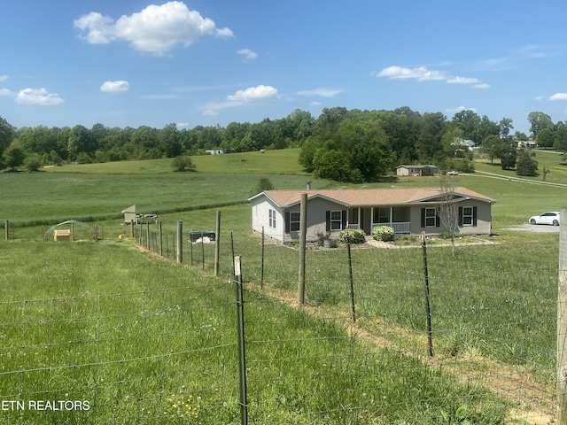 view of front of house with fence, a front yard, and a rural view
