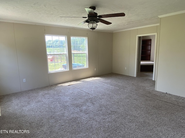 carpeted empty room featuring crown molding, a textured ceiling, and a ceiling fan