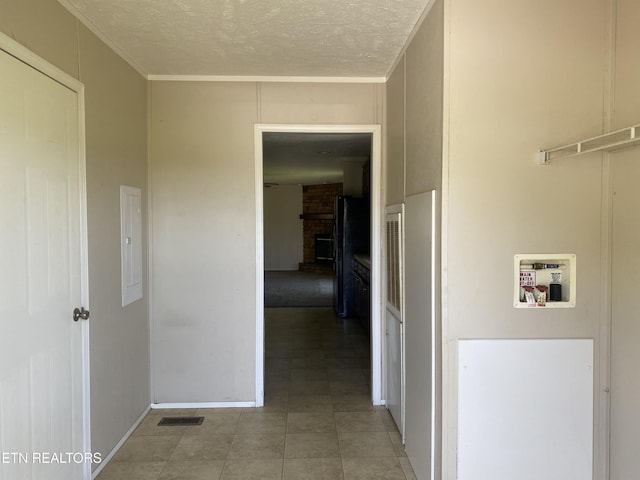 hallway featuring a textured ceiling, visible vents, and ornamental molding