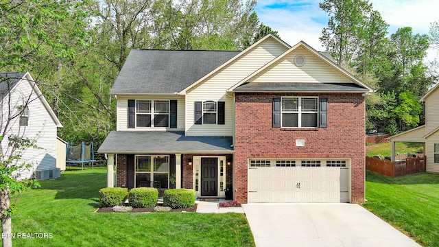 view of front of property featuring a front yard, brick siding, concrete driveway, an attached garage, and a trampoline