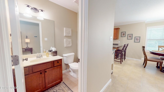 bathroom featuring toilet, baseboards, ornamental molding, and vanity
