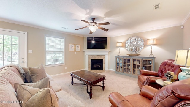 living area with visible vents, crown molding, a fireplace, ceiling fan, and light colored carpet