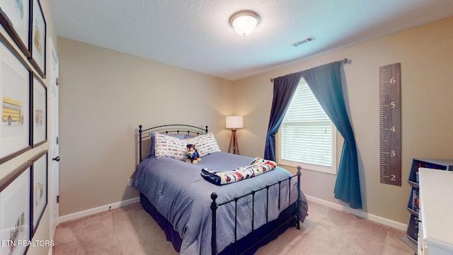 carpeted bedroom with visible vents, a textured ceiling, and baseboards