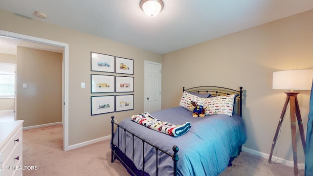 bedroom with light colored carpet, a textured ceiling, and baseboards