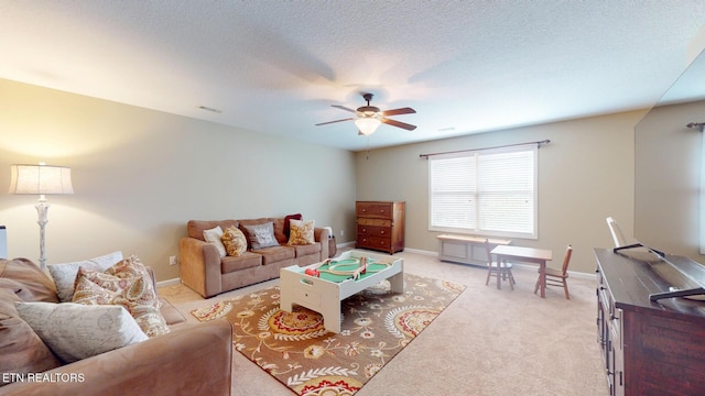 living area featuring visible vents, baseboards, ceiling fan, light colored carpet, and a textured ceiling
