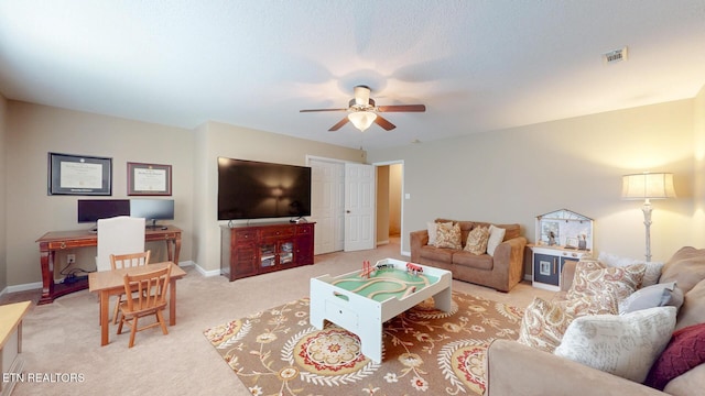 living room featuring light colored carpet, ceiling fan, visible vents, and baseboards