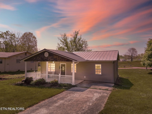 view of front of home featuring a porch, a standing seam roof, metal roof, a front yard, and concrete driveway