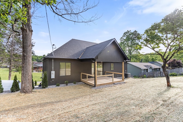 view of front of home with fence, cooling unit, a shingled roof, and a wooden deck