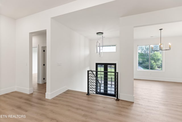 entryway with light wood-type flooring, baseboards, and a chandelier