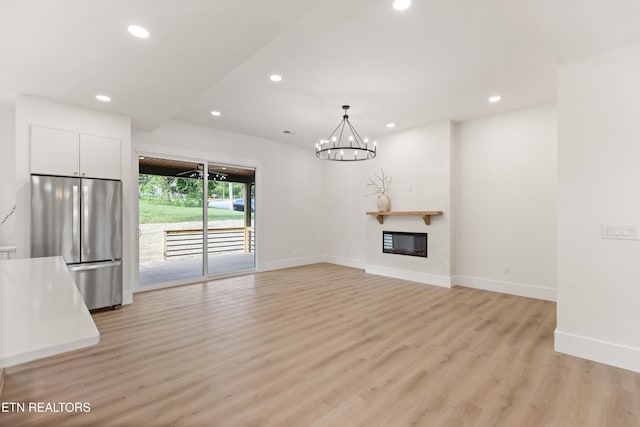 unfurnished living room featuring an inviting chandelier, baseboards, recessed lighting, and light wood-style flooring