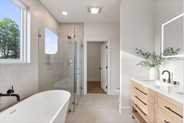 bathroom with a freestanding bath, vanity, toilet, tile patterned floors, and a shower stall