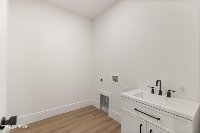 clothes washing area with cabinet space, a sink, light wood-style floors, hookup for a washing machine, and hookup for an electric dryer