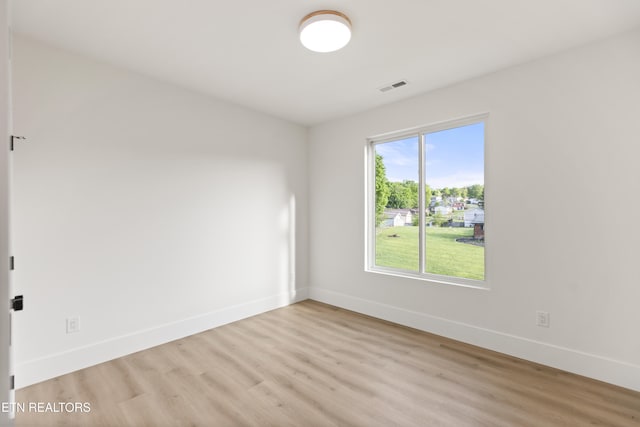 spare room featuring visible vents, light wood-style floors, and baseboards
