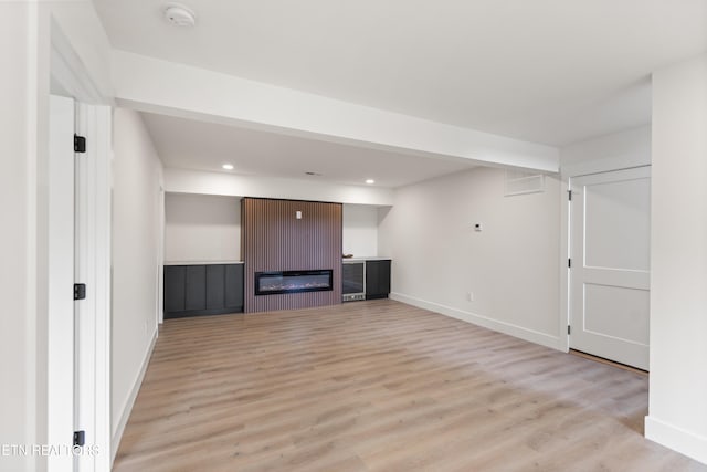 unfurnished living room with recessed lighting, baseboards, and light wood finished floors