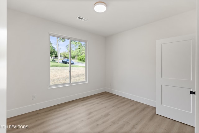 empty room featuring visible vents, baseboards, and light wood-type flooring