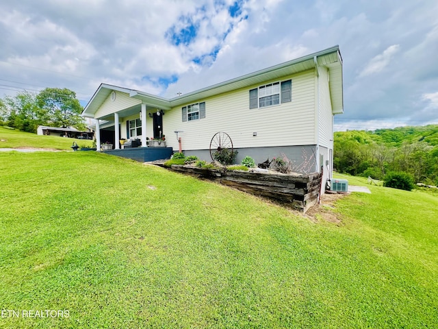back of property with central AC, a porch, and a lawn