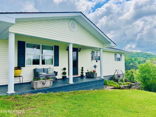 rear view of property featuring a porch and a lawn