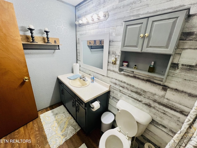 half bathroom featuring wood finished floors, vanity, and toilet