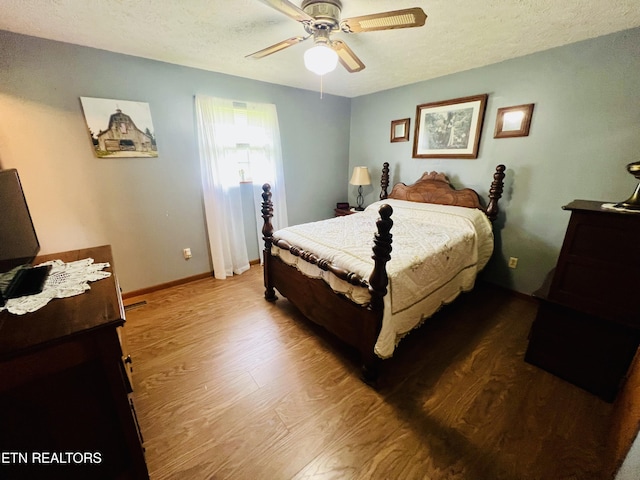bedroom with a textured ceiling, wood finished floors, a ceiling fan, and baseboards
