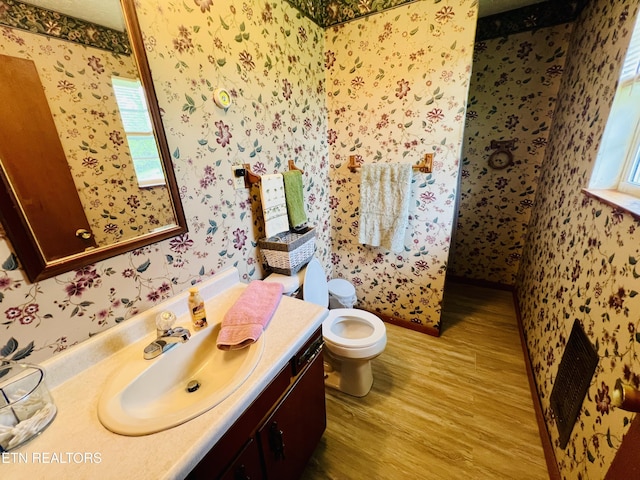 bathroom featuring wallpapered walls, wood finished floors, toilet, and vanity