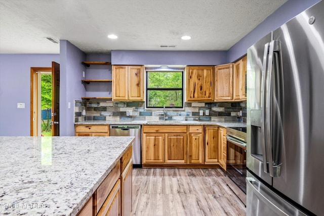 kitchen featuring a sink, tasteful backsplash, stainless steel appliances, and light wood-type flooring
