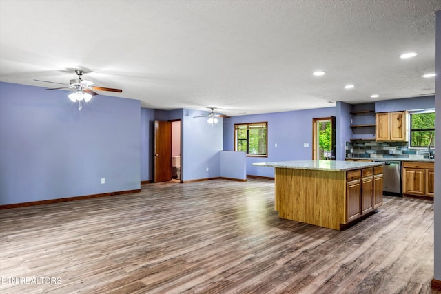 kitchen featuring stainless steel dishwasher, a ceiling fan, baseboards, and a center island