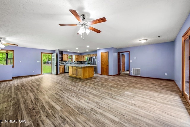 kitchen featuring visible vents, wood finished floors, open floor plan, a ceiling fan, and appliances with stainless steel finishes