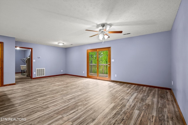 spare room featuring baseboards, ceiling fan, visible vents, and wood finished floors