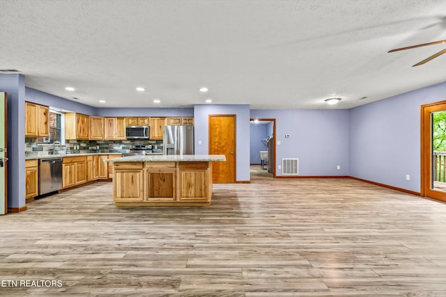 kitchen featuring light countertops, a textured ceiling, stainless steel appliances, light wood-type flooring, and visible vents