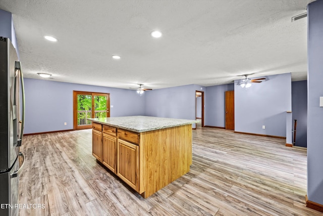kitchen with a textured ceiling, ceiling fan, stainless steel fridge with ice dispenser, and light wood-type flooring